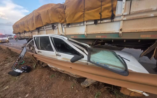 Fiat Uno fica prensado entre caminhão e defensa metálica após acidente