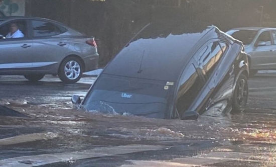 Carro cai em cratera após adutora de água se romper na Av. Independência, em Goiânia