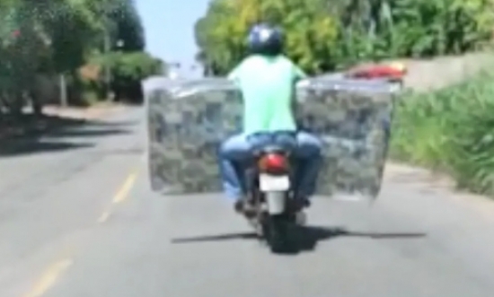 Motociclista se desdobra para carregar colchão e pilotar moto