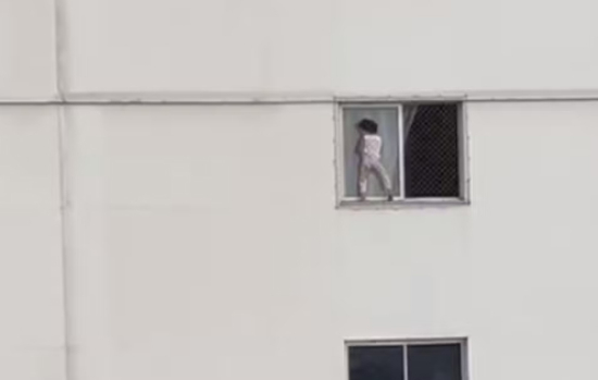 Criança brinca se apoiando em tela de proteção de janela em apartamento do 4º andar